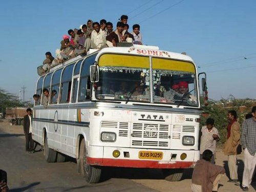 piucture of an indian tata bus with people on the seats in the aisle and on the roof